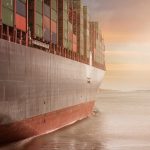 cargo ship in water overlooking sunset