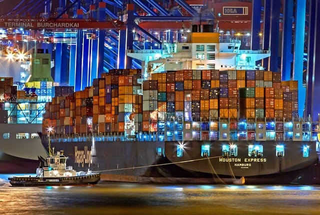 A ship full of containers at port during the night.